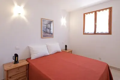 a bedroom with a bed with a red blanket and a window at Villa CASA CALLISTA , confort et calme in Sainte-Lucie de Porto-Vecchio