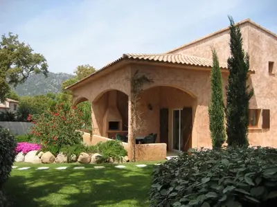 a large stone house with a garden in front of it at Villa CASA CALLISTA , confort et calme in Sainte-Lucie de Porto-Vecchio