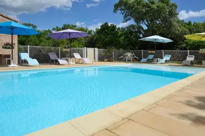 a large swimming pool with chairs and umbrellas at Villa CASA CALLISTA , confort et calme in Sainte-Lucie de Porto-Vecchio