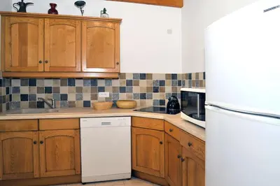 a kitchen with wooden cabinets and a white refrigerator at Villa CASA CALLISTA , confort et calme in Sainte-Lucie de Porto-Vecchio