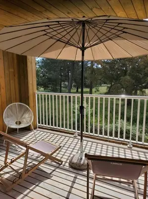 a porch with an umbrella and chairs and a table at Superbe T2 neuf 42m² Cala Rossa (proche mer) in Lecci