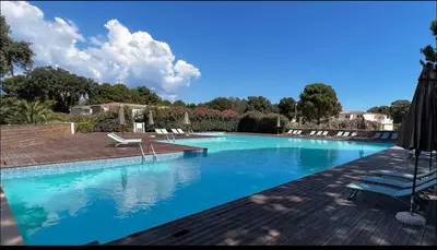 a large blue swimming pool with chairs and an umbrella at Superbe T2 neuf 42m² Cala Rossa (proche mer) in Lecci