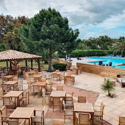 a patio with tables and chairs and a swimming pool at Superbe T2 neuf 42m² Cala Rossa (proche mer) in Lecci