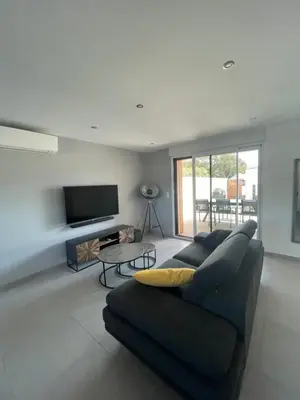 a living room with a couch and a flat screen tv at Maison neuve Porto Vecchio in Porto-Vecchio
