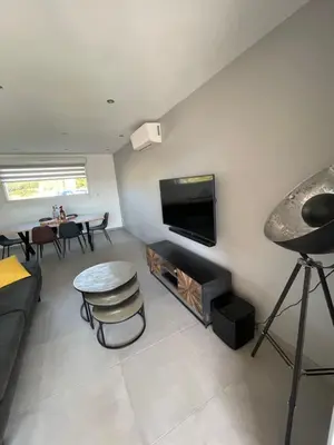 a living room with a couch and a tv on the wall at Maison neuve Porto Vecchio in Porto-Vecchio