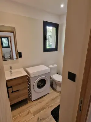 a bathroom with a washing machine and a toilet at Belle villa à la campagne dans un coin cosy in Sartène