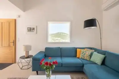 a blue couch in a living room with a vase of flowers at VILLA MYRTE A CIRINDINU in Cirendinu