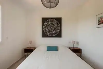 a bedroom with a bed with two tables and a clock at VILLA MYRTE A CIRINDINU in Cirendinu