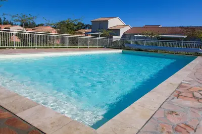 a swimming pool with blue water in front of a fence at Villa climatisée T3 piscine chauffée accès direct à la plage de Prunete in Cervione