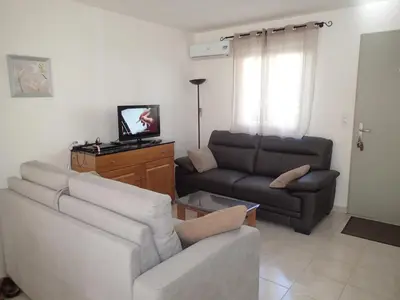 a living room with a couch and a tv at Villa climatisée T3 piscine chauffée accès direct à la plage de Prunete in Cervione