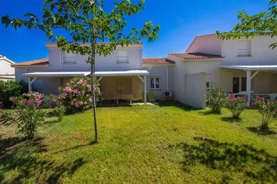 a house with a green yard in front of it at Villa climatisée T3 piscine chauffée accès direct à la plage de Prunete in Cervione