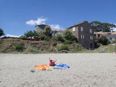 a towel and a bucket on a sandy beach at Villa climatisée T3 piscine chauffée accès direct à la plage de Prunete in Cervione