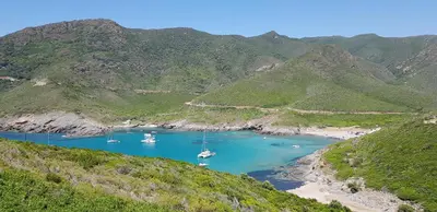a group of boats in a bay with mountains at Villa climatisée T3 piscine chauffée accès direct à la plage de Prunete in Cervione