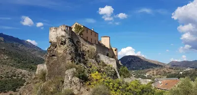 a castle perched on top of a mountain at Villa climatisée T3 piscine chauffée accès direct à la plage de Prunete in Cervione