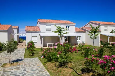 a large white house with pink flowers in the yard at Villa climatisée T3 piscine chauffée accès direct à la plage de Prunete in Cervione