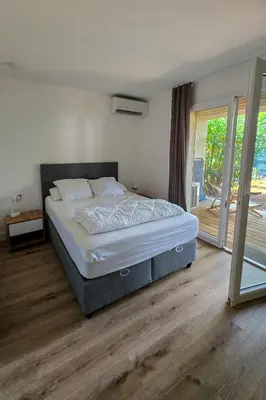a bedroom with a bed and a sliding glass door at Fiori Di Cala Rossa, Établissement CARDOGA Piscine, Mer & Montagne in Lecci