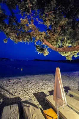 a table and a chair on a beach at night at Fiori Di Cala Rossa, Établissement CARDOGA Piscine, Mer & Montagne in Lecci