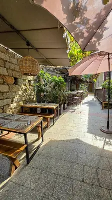 a patio with tables and chairs and an umbrella at Fiori Di Cala Rossa, Établissement CARDOGA Piscine, Mer & Montagne in Lecci