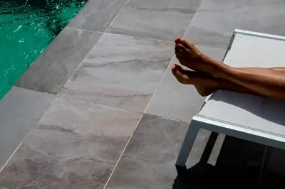 a persons legs sitting on a chair next to a swimming pool at VILLA A MUREDDA, piscine chauffée et vue mer in Olmeto