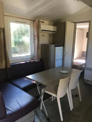 a dining room with a table and chairs and a kitchen at PROCHE du PONT GENOIS in Sartène