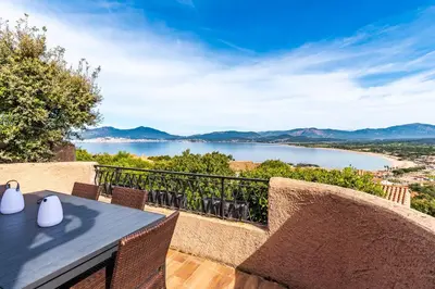 a table and chairs on a balcony with a view of a lake at Terra Di Sole - Vue mer et montagne in Grosseto-Prugna