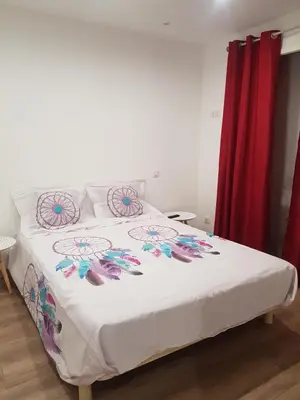 a bedroom with a bed with white sheets and colorful pillows at Maison T2 500m de la plage in Poggio-Mezzana