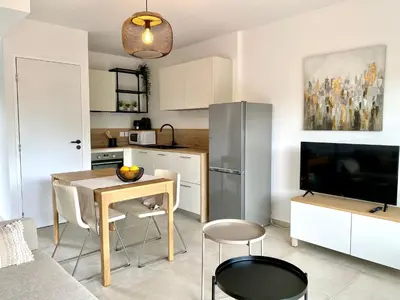 a kitchen with a table and chairs and a television at L'Ondella T2 Porticcio et Garage in Porticcio