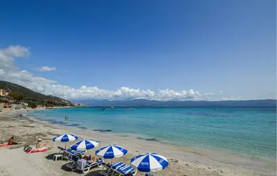 a beach with blue and white umbrellas and the ocean at 2 Bedroom Lovely Home In Piscia Rossa in Afa