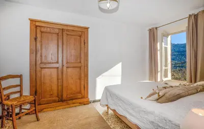 a bedroom with a bed and a window and a chair at Awesome Home In San-Gavino Di Carbini in San-Gavino-di-Carbini
