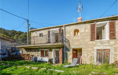 an old stone house with a chair in front of it at Awesome Home In San-Gavino Di Carbini in San-Gavino-di-Carbini
