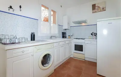 a kitchen with white cabinets and a washer and dryer at Stunning Home In Afa With Wifi in Afa