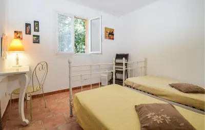 a bedroom with two beds and a desk and a window at Cozy Home In Piscia Rossa With Wifi in Afa
