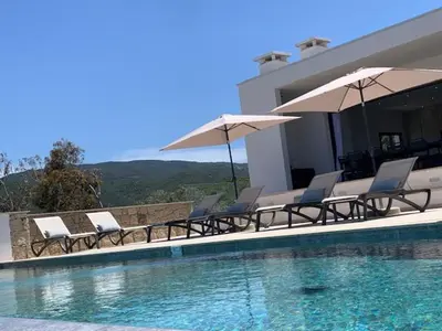 a group of chairs and umbrellas next to a swimming pool at VILLA RIVOLI vue mer et piscine in Pietrosella
