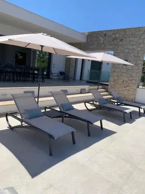a group of chairs and umbrellas on a patio at VILLA RIVOLI vue mer et piscine in Pietrosella