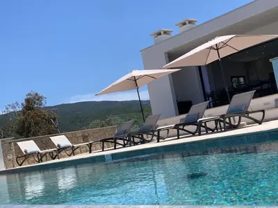 a group of chairs and umbrellas next to a swimming pool at VILLA RIVOLI vue mer et piscine in Pietrosella