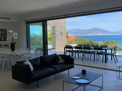 a living room with a couch and a dining room at VILLA RIVOLI vue mer et piscine in Pietrosella
