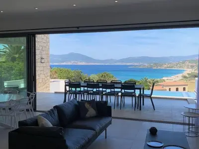 a living room with a couch and a view of the ocean at VILLA RIVOLI vue mer et piscine in Pietrosella