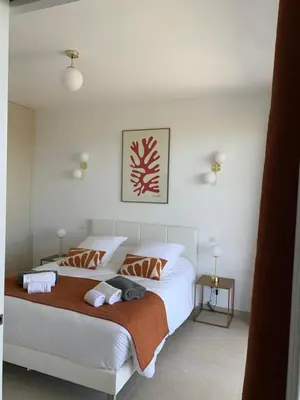 a bedroom with a bed with white sheets and orange pillows at VILLA NAPOLEON vue mer et piscine in Pietrosella