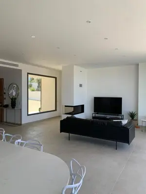 a living room with a black couch and a flat screen tv at VILLA NAPOLEON vue mer et piscine in Pietrosella