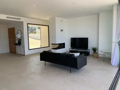 a living room with a black couch and a flat screen tv at VILLA NAPOLEON vue mer et piscine in Pietrosella
