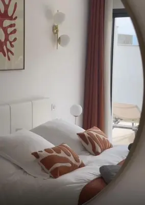 a bed with white sheets and pillows in front of a mirror at VILLA NAPOLEON vue mer et piscine in Pietrosella