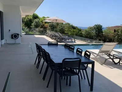 a black table and chairs next to a swimming pool at VILLA NAPOLEON vue mer et piscine in Pietrosella