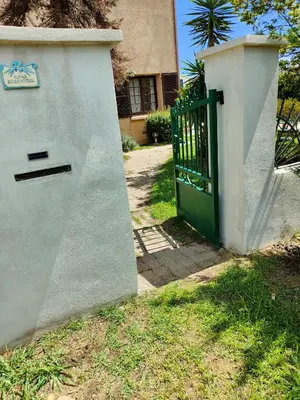 a green gate in front of a house at Maison de campagne piscine et jardin privatifs près de la plage in Aléria