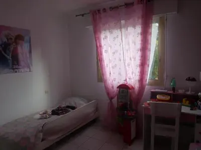 a bedroom with a bed and a window with pink curtains at Appartement 3 chambres - 2 salles de bain - 6 personnes in Ajaccio