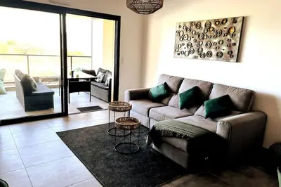 a living room with a couch and two tables at Appartement avec terrasse 3 pièces - Vue mer - Plage 5 min à pied in Propriano