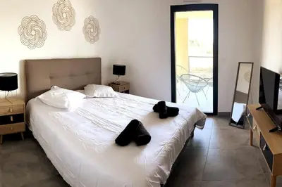 a bedroom with a white bed with black shoes on it at Appartement avec terrasse 3 pièces - Vue mer - Plage 5 min à pied in Propriano