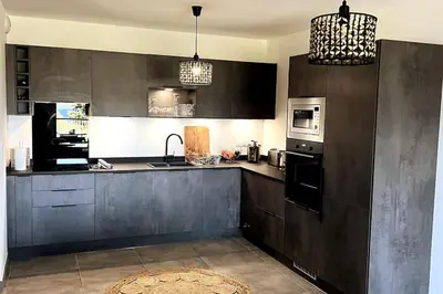 a large kitchen with black cabinets and appliances at Appartement avec terrasse 3 pièces - Vue mer - Plage 5 min à pied in Propriano
