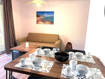 a dining room with a table and a couch at Cala Rossa T2 Neuf à 800 m de la mer appart n 81 in Lecci