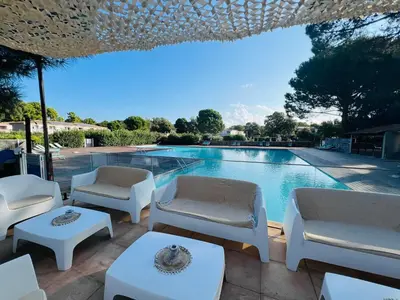 a swimming pool with white chairs and a table at Cala Rossa T2 Neuf à 800 m de la mer appart n 81 in Lecci