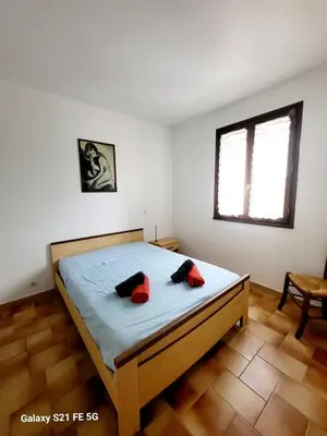 a bedroom with a bed with two red pillows on it at T2 bord de mer Agosta in Albitreccia
